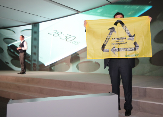 세계 최대 모바일 전시회 '모바일 월드 콩그레스(이하 MWC) 2017' 개막 하루 전인 26일(현지시간) 스페인 바르셀로나 카탈루냐 콩그레스 센터에서 열린 삼성 신제품 공개 행사에서 데이비드 로우즈 삼성전자 유럽법인 최고마케팅책임자(CMO)(왼쪽)가 프리젠테이션을 하던 중 그린피스 관계자로 추정되는 남성이 갤럭시노트7의 환경친화적인 재활용을 촉구하며 현수막을 펼쳐 보이고 있다. 이 남성은 로우즈 CMO의 요청에 별다른 항의 없이 무대를 떠났다.